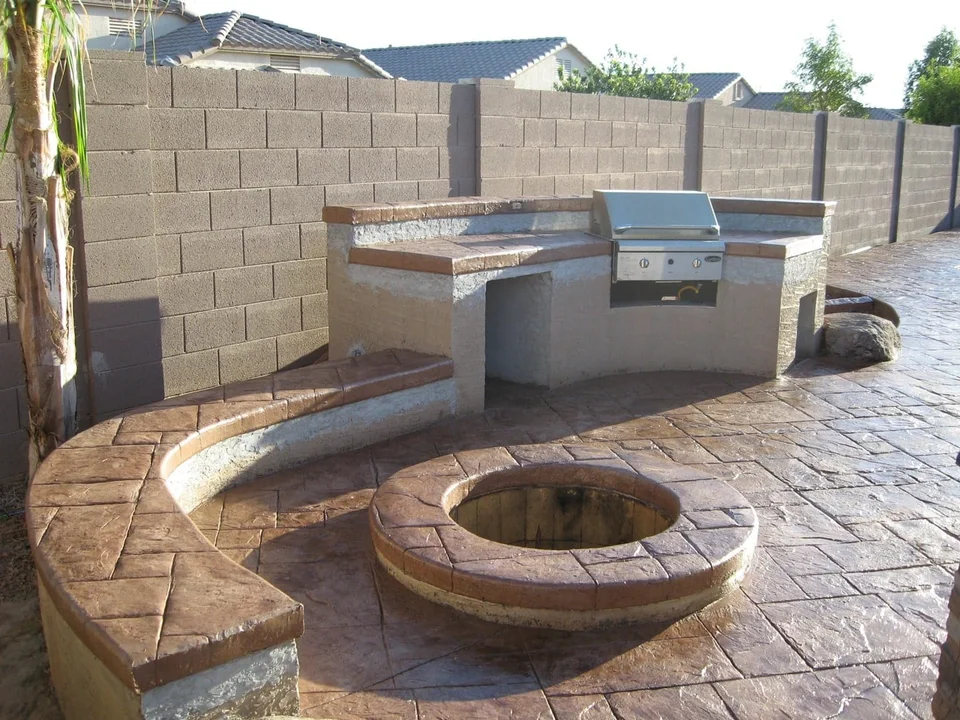 An outdoor cooking area and a circular fire feature share one sitting space.