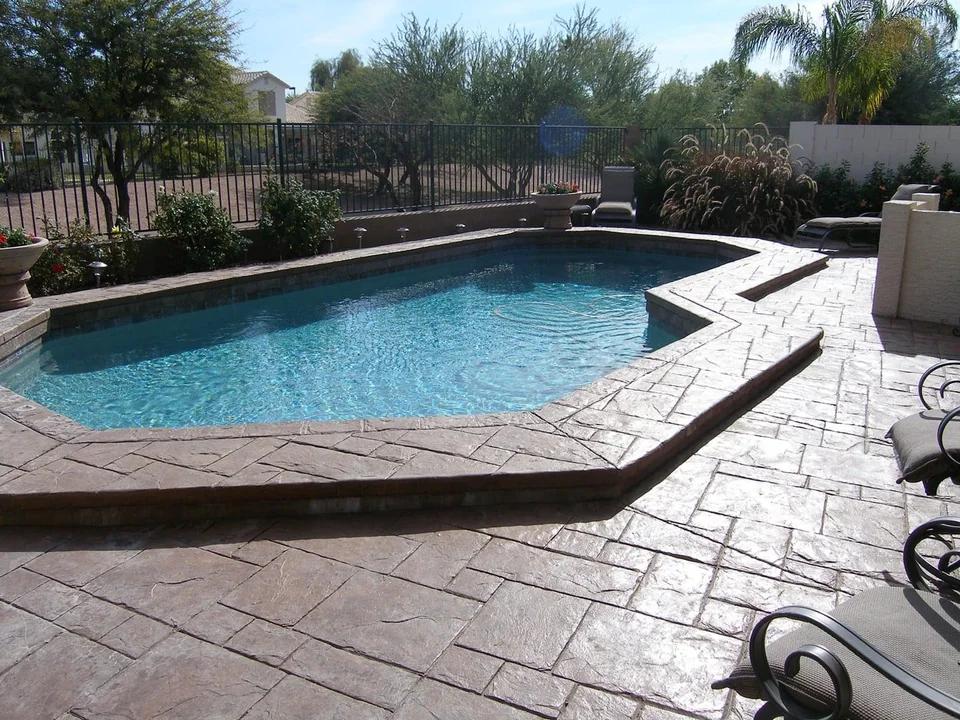 A broad outdoor surface links the pool edge and surrounding seating areas.